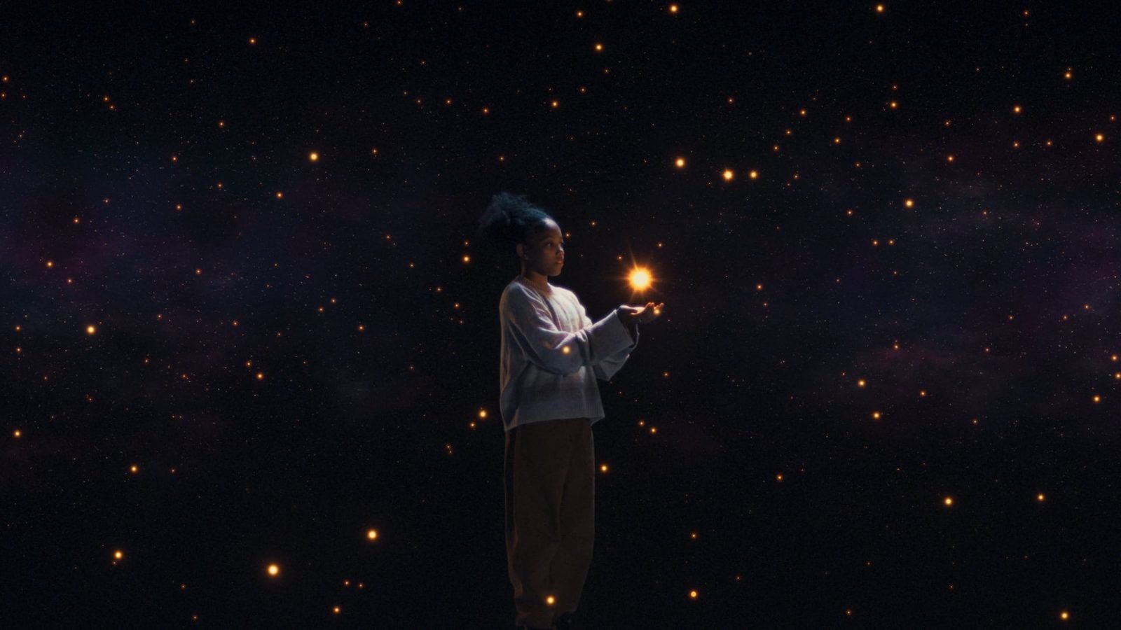 A girl holds a glowing light in her palm among drifting stars