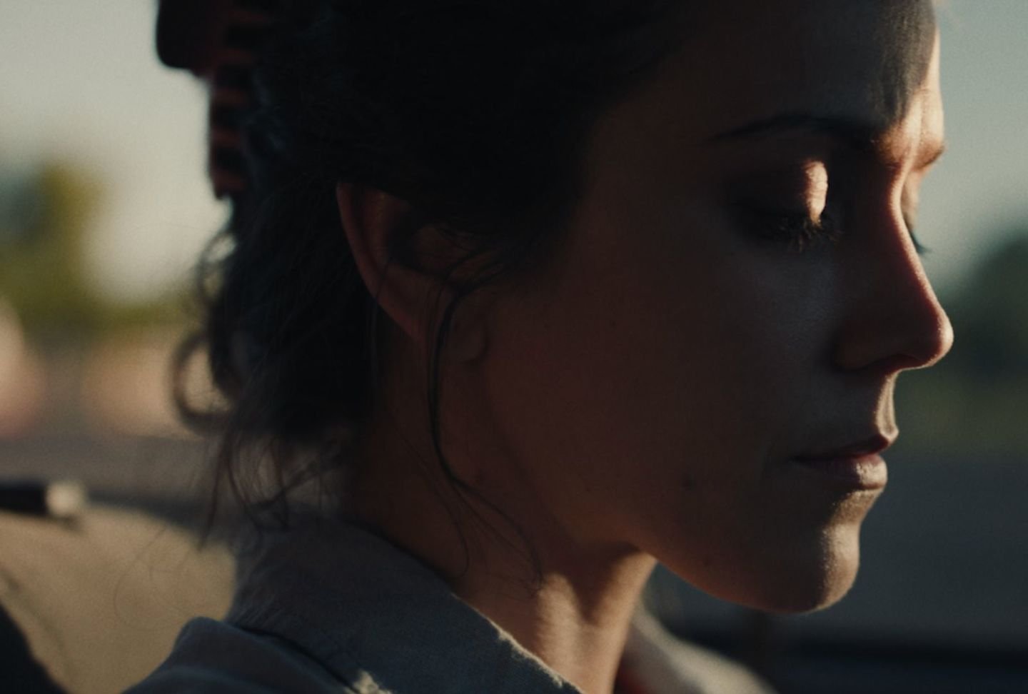 A woman in profile with her eyes closed, lit by low evening sun